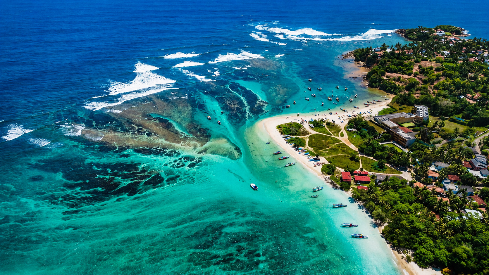Aerial view of Weligama Bay with turquoise water, coral reefs and palm-lined coast