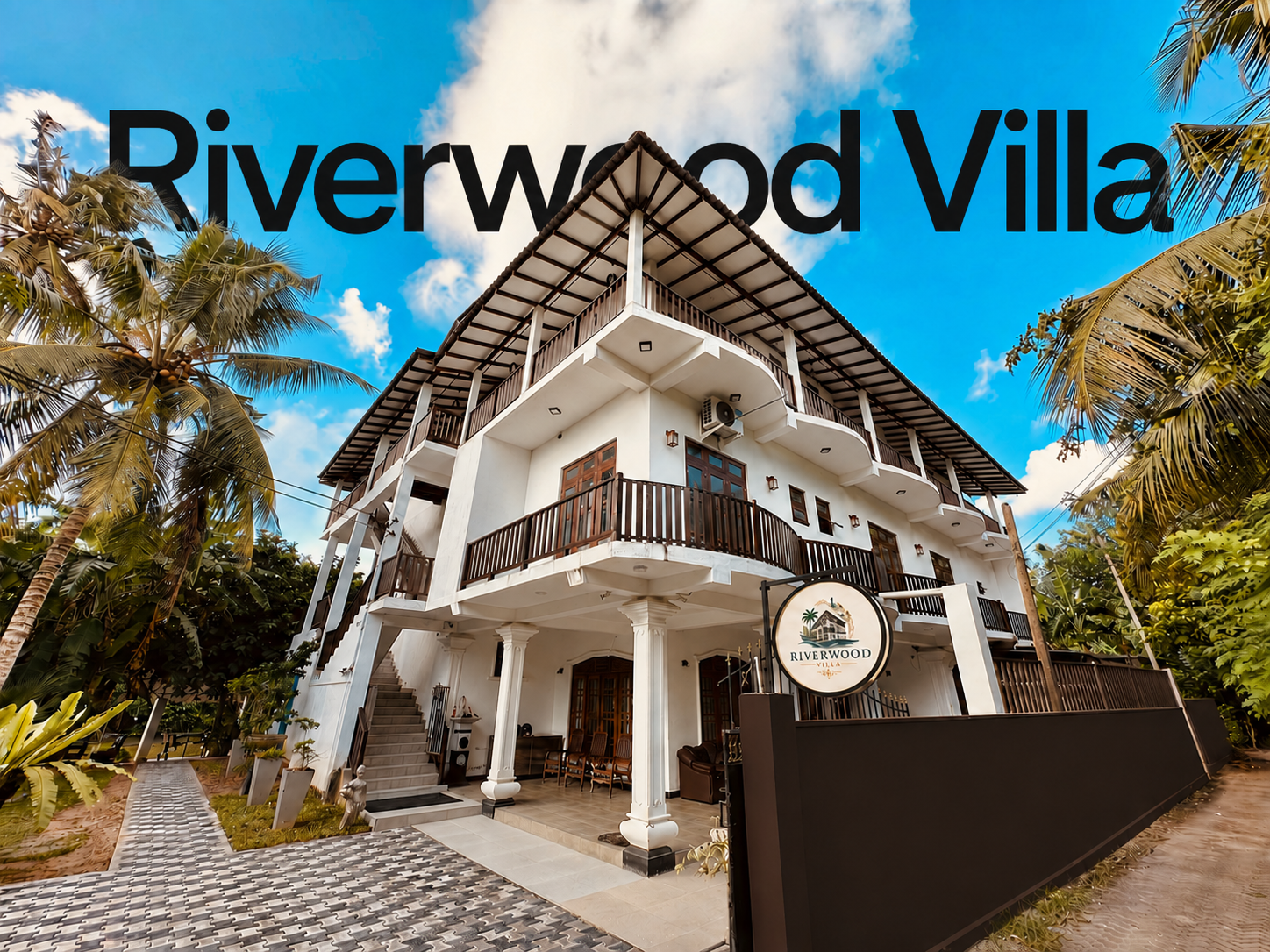 Front exterior of Riverwood Villa with palm trees and sign